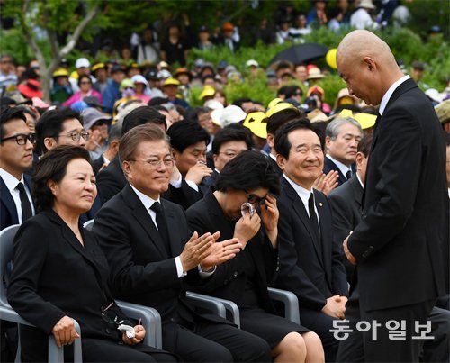 노건호씨 “탈모 심해 삭발” 노무현 전 대통령의 아들 노건호 씨(오른쪽)가 23일 경남 김해시 
봉하마을에서 열린 노 전 대통령 8주기 추도식에서 유족 인사를 마치고 연단에서 내려오자 문재인 대통령이 박수를 치며 격려하고 
있다. 문 대통령 왼쪽은 권양숙 여사, 오른쪽은 눈물을 훔치는 김정숙 여사, 정세균 국회의장. 김해=변영욱 기자 cut@donga.com