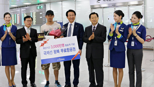 12일 부산 김해국제공항에서 에어부산 한태근 사장(가운데)이 3000만 번째 탑승객인 중국인 관광객에게 축하 선물을 증정하고 있다. 에어부산 제공