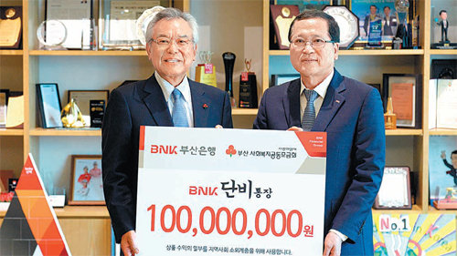 BNK금융그룹 산하 부산은행 홍성표 부행장(오른쪽)이 지난달 ‘BNK단비·바람통장’ 판매수익금의 일부를 부산사회복지공동모금회 신정택 회장에게 전달하고 있다. 부산은행 제공