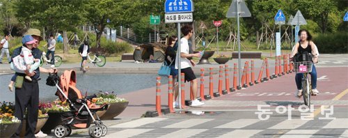 13일 서울 영등포구 여의도한강공원 물빛광장 인근 자전거도로에서 커플용 자전거 이용자들이 횡단보도를 건너는 보행자 앞을 지나치려 
하고 있다. 왼쪽 뒤편 광장에도 자전거와 보행자가 뒤섞여 있다. 변영욱 기자 cut@donga.com