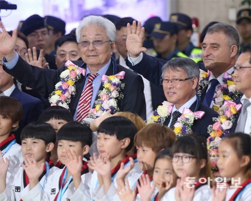 북한의 장웅 국제올림픽위원회(IOC) 위원(뒷줄 왼쪽)이 23일 김포국제공항으로 입국한 뒤 환영하러 나온 국내 어린이 태권도 선수들과 함께 손을 흔들고 있다. 박영대 기자 sannae@donga.com