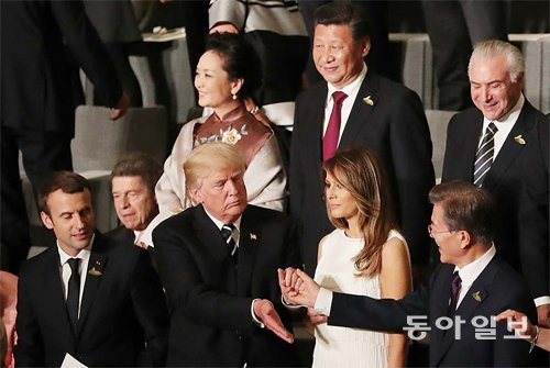 도널드 트럼프 미국 대통령(앞줄 왼쪽에서 두 번째)이 7일(현지 시간) 독일 함부르크 엘브필하모니에서 열린 G20 정상회의 
문화공연에서 문재인 대통령과 손을 잡고 인사를 나누고 있다. 이날 트럼프 대통령은 문 대통령에게 먼저 손을 내밀었고, 문 대통령의
 오른손을 두 번 톡톡 치며 친근감을 표시했다. 뒷줄의 시진핑 중국 국가주석(뒷줄 왼쪽에서 두 번째)은 정면을 응시하고 있다. 
함부르크=원대연 기자 yeon72@donga.com