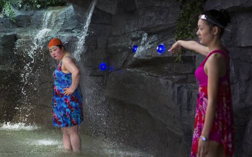 평양 해당화관 3층 물놀이장의 인공폭포에서 여성 2명이 더위를 식히고 있다. 사진 출처 저널센티널