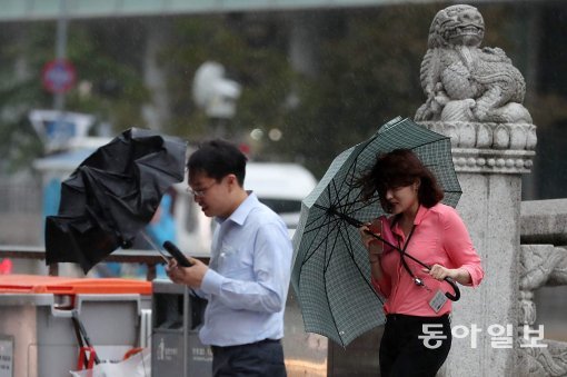 강한 비바람이 몰아친 24일 오후 서울 종로구 청계광장을 지나던 시민들이 강풍으로부터 우산을 지키느라 애를 쓰고 있다. 전영한 기자 scoopjyh@donga.com