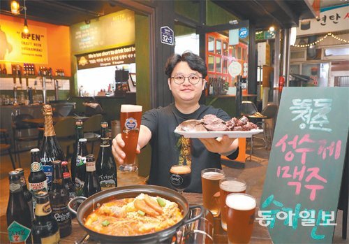 서울 뚝도시장에서 수제 맥줏집을 운영하는 청년상인 김성현 대표가 가게에서 파는 맥주와 함께 순대를 들어 보이고 있다. 순대와 테이블에 놓인 떡볶이 모두 시장 내 이웃 가게에서 가져온 것이다. 김 대표는 수제 맥주와 시장 먹거리를 함께 즐기는 상생 전략으로 주목받고 있다. 장기적으로는 ‘전통시장 속 수제 맥줏집’을 여러 곳 내는 게 그의 목표다. 전영한 기자 scoopjyh@donga.com