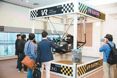 2016 넥스트 콘텐츠 콘퍼런스 체험관에서 피엔아이 시스템의 VR 레이싱 시뮬레이터를 체험하는 관람객.