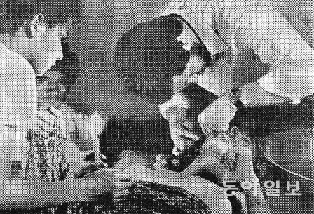 콜롬비아 화산폭발현장에서 의료요원이 촛불 아래서 환자를 치료하는 모습. 동아일보 지면 캡처