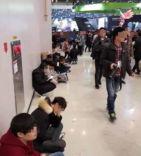 휴식공간이 없어 바닥에 앉아 쉬고있는 관람객들 / 게임동아