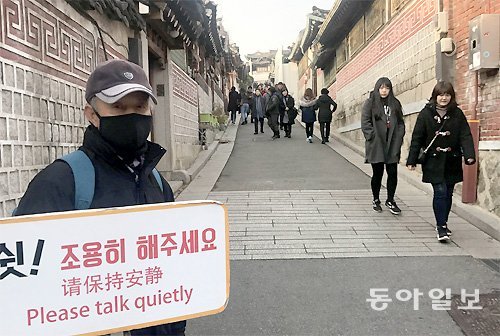 관광객으로 붐비는 서울 종로구 북촌한옥마을에서 안내원이 한국어 중국어 영어로 ‘조용히 해달라’고 적힌 팻말을 들고 서 있다. 황태호 기자 taeho@donga.com