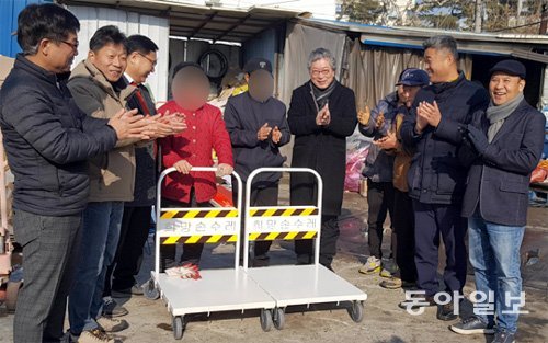 캐리커처 모델이 된 인연으로 모인 ‘희망얼굴’ 조동욱 회장(왼쪽에서 세 번째)과 회원들이 21일 폐지를 줍는 노인 2명에게 ‘희망 손수레’를 전달하고 있다. 희망얼굴 회원들이 십시일반 모은 돈으로 만들었다. 청주=장기우 기자 straw825@donga.com