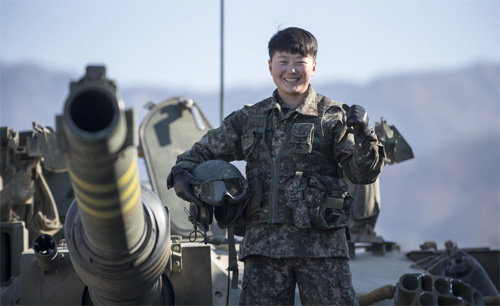 여군 최초의 전차 조종수인 임현진 하사가 12일 경기 포천 일대 훈련장에서 K-1A2 전차 위에 올라가 헬멧을 들고 포즈를 취하고있다. 육군 제공
