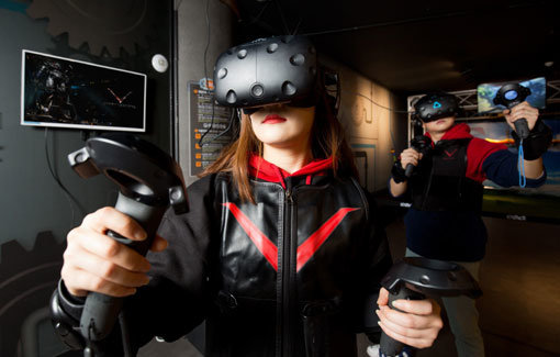 ‘로보트 태권V’ VR 게임에서 이용자가 고글과 헤드폰을 쓰고 촉감조끼와 팔토시를 착용한 뒤 컨트롤러를 통해 가상현실 속 태권V를 조종하고 있다. 사진제공｜롯데월드