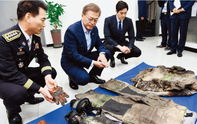 문재인 대통령(가운데)이 지난해 6월 서울 용산소방서를 방문해 소방관들이 사용했던 장비를 살펴보고 있다. [동아일보]