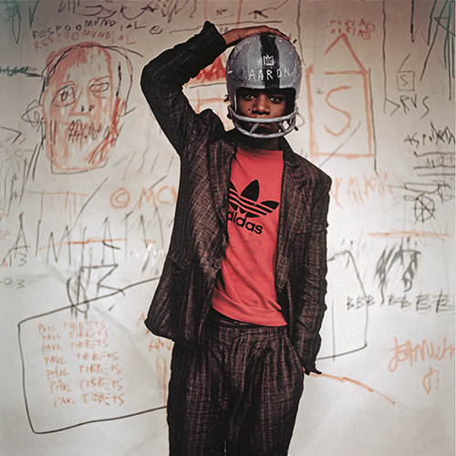 흑인 야구 영웅 ‘행크 아론’의 이름위에 왕관을 그려 넣은 헬멧을 쓰고 작품 앞에 서 있는 장-미셸 바스키아(1981). 그의 작품에서는 흑인 우상을 향한 존경심을 자주 발견할 수 있다.- 바비칸 아트 갤러리 제공·ⓒThe Estate of Jean-Michel Basquiat, Licensed by Artestar, New York