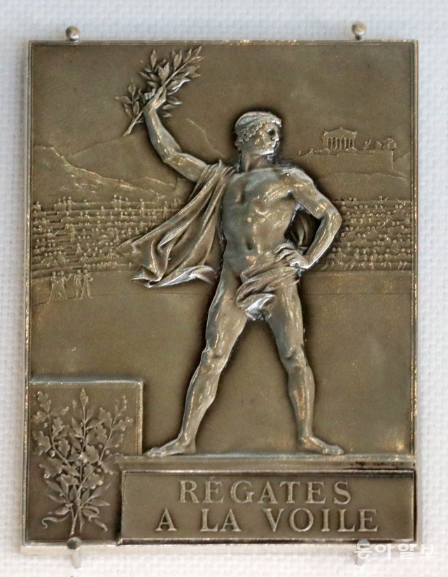 1900년 프랑스 하계 조정경기 우승메달. 프랑스 파리 세느강 일대에서 8개국 108명의 선수가 참가. 남자 경기만 진행되었다. 프랑스에서 금메달 2개를 획득하여 1위를 했다.