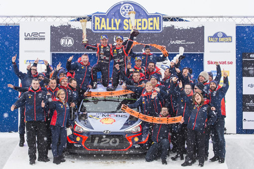 2018 WRC 스웨덴 랠리에서 시상대에서 현대 월드랠리팀 선수 및 관계자들의 기념사진. 신형 i20 랠리카 위에서 니콜라스 질술(Nicolas Gilsoul, 왼쪽)과 티에리 누빌(Thierry Neuville)이 우승컵을 들고 환호하는 모습.
사진제공｜현대자동차