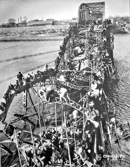 6·25전쟁 당시 파괴된 대동강 다리 잔해를 기어올라 강을 건너는 피란민들을 촬영한 맥스 데스퍼의 사진. 동아일보DB
