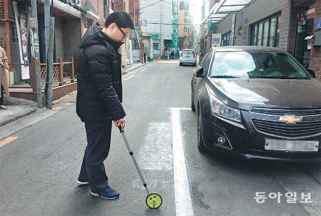 지난달 22일 서울 마포구 직원이 거주자우선주차구역이 설치된 도로 폭을 재고 있다. 마포구는 도로 너비가 5.5m 미만인 곳의 거주자우선주차구역은 모두 지우기로 했다. 김단비 기자 kubee08@donga.com