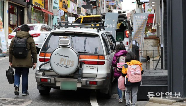 상가-차량 틈새로 학교 다녀 불법 주차 차량이 보행 공간을 차지하면서 하굣길 어린이들이 비좁은 차량 틈으로 걸어가고 있다. 대전=전영한 기자 scoopjyh@donga.com