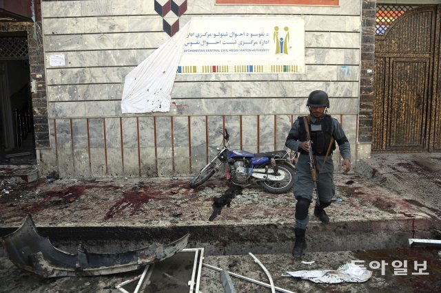 An Afghan police walks outside a voter registration center which was attacked by a suicide bomber in Kabul, Afghanistan, Sunday, April 22, 2018.  Gen. Daud Amin, the Kabul police chief, said the suicide bomber targeted civilians who had gathered to receive national identification cards. (AP Photo/ Rahmat Gul)