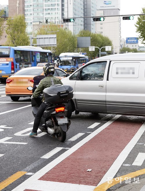 버스 뒤로 위태하게 길을 건너는 자전거 이용자와 혼잡한 교통 상황 때문에 자전거로 다닐 수 없는 자전거 우선도로. 자전거전용차로를 침범하는 오토바이는 쉽게 목격된다. 홍중식 기자 free7402@donga.com