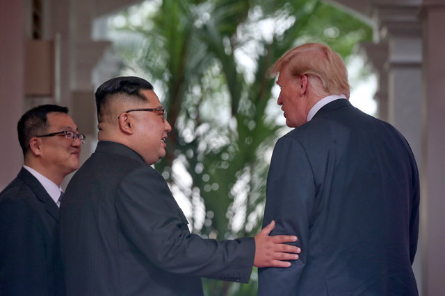 김정은 북한 국무위원장이 12일 싱가포르 북-미 정상회담에서 처음 대면한 도널드 트럼프 미국 대통령의 왼팔을 잡고 친근감을 표시하고 있다. 싱가포르 정부 제공
