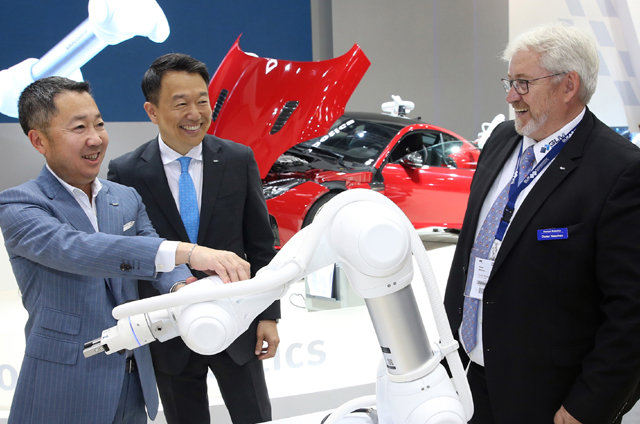 박정원 두산그룹 회장(왼쪽)과 이병서 두산로보틱스 대표(가운데)가 19∼22일 독일 뮌헨에서 열린 오토매티카 두산로보틱스 부스에서 독일 로봇 시장 딜러 업체 대표와 협동로봇에 대해 이야기를 나누고 있다. 두산그룹 제공