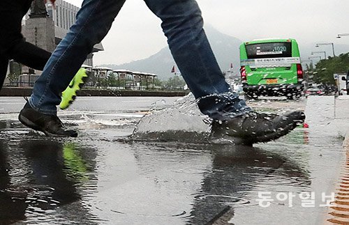 전국에 장마가 시작된 26일 오후 서울시 세종로에서 시민들이 우산을 쓰고 물이 고인 도로를 건너고 있다. 전영한 기자 scoopjyh@donga.com