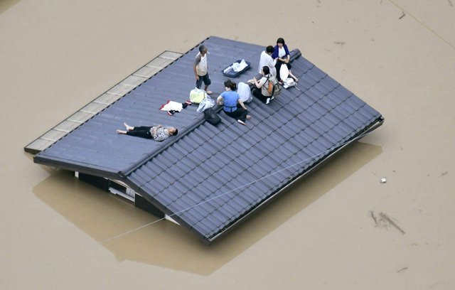 일본에 내린 기록적 폭우로 홍수가 난 오카야마 현 구라시키 시에서 지붕 위에 올라 구조를 기다리는 일본 주민들. 구라시키=AP 뉴시스