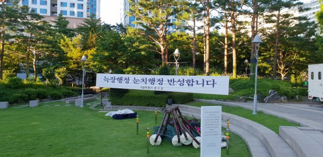 30일 서울 중구청 잔디광장 앞에 내걸린 사과 플래카드와 수거된 그늘막. 이날 중구는 기자회견을 열어 “서울시 간부의 요구로 다른 곳보다 시청 앞에 그늘막이 먼저 설치됐다”며 구정을 반성한다고 밝혔다. 중구청 제공