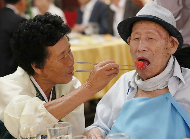 “아버지 맛있게 드세요” 20일 북한 금강산호텔에서 열린 이산가족 상봉 만찬에서 안정순 씨(70·왼쪽)가 남측에서 올라온 아버지 안종호 씨(100)에게 음식을 건네고 있다. 금강산=사진공동취재단