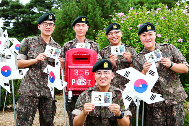 육군 36사단 신병교육대대 장병들이 부모님께 보낼 ‘나만의 엽서’를 들어보이며 활짝 웃고 있다. 육군 36사단 제공