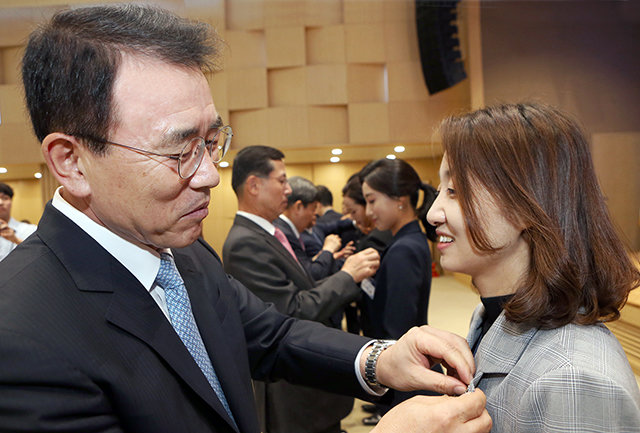 3일 서울 중구 신한금융 본사에서 열린 창립 17주년 기념식에서 조용병 신한금융그룹 회장(왼쪽)이 직원에게 ‘원 신한’ 배지를 달아주고 있다. 신한금융지주 제공