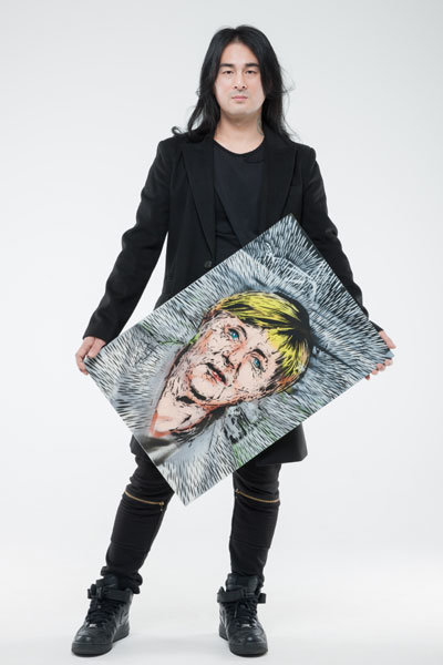 독일 앙겔라 메르켈 총리를 그린 작품을 들고 있는 닌볼트 작가. 사진제공｜글로벌엔터