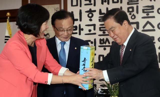 이정미 정의당 대표가 21일 서울 여의도 국회 국회의장실에서 열린 국회의장과 평양남북정상회담 특별수행한 3당 대표 회동에 앞서 문희상 국회의장에게 ‘류경술’을 선물하고 있다. 왼쪽 부터 이정미 정의당 대표, 이해찬 더불어민주당 대표, 문희상 의장. © News1