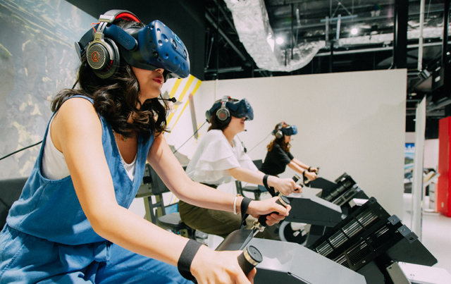 일본 반다이남코가 운영하고 있는 가상현실(VR) 테마파크 ‘VR 존 오사카’에서 이용자들이 VR 기기 ‘공중자전거’를 체험하고 있는 모습. 현대IT&E 제공