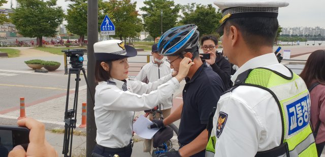 자전거 헬멧 착용 의무화 시행 첫날인 28일 오전, 서울 영등포구 여의도 한강공원에서 홍보활동에 나선 경찰이 한 시민에게 헬멧을 나눠주고 있다. © News1