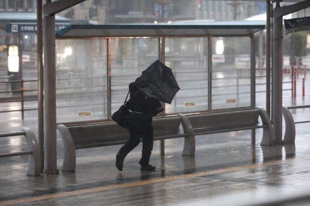 우산을 펴기 위해 애쓰고 있는 일본인 남성. © AFP=뉴스1