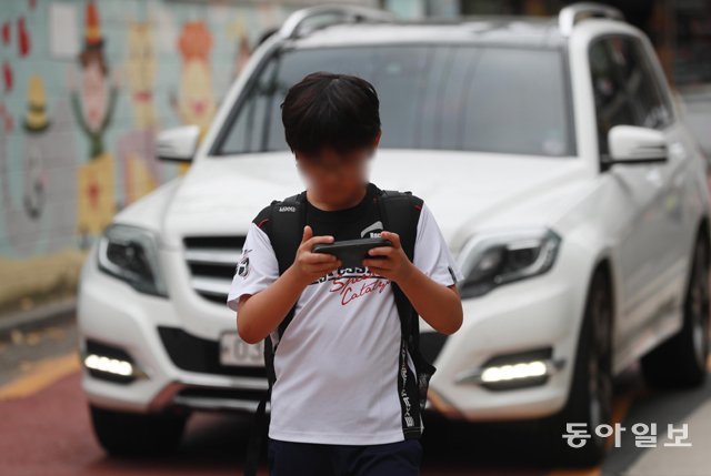 14일 서울 마포구의 한 초등학교 앞 어린이보호구역(스쿨존)에서 하교 중인 초등학생이 스마트폰 화면을 쳐다보며 걷고 있다. 이 곳은 차량 통행이 많아 어린 학생들의 각별한 주의가 필요하다. 박영대 기자 sannae@donga.com