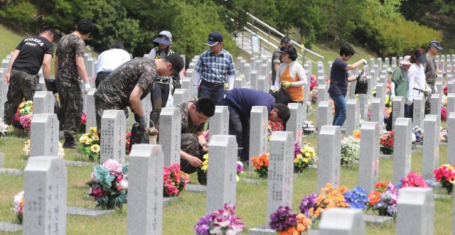 6.25 한국전쟁 발발 68주년을 닷새 앞둔 20일 오후 국립대전현충원을 찾은 육군본부 기록정보관리단 장병들과 군무원들이 참배를 마치고 사병2묘역에서 정화활동을 펼치고 있다. 2018.6.20/뉴스1 © News1