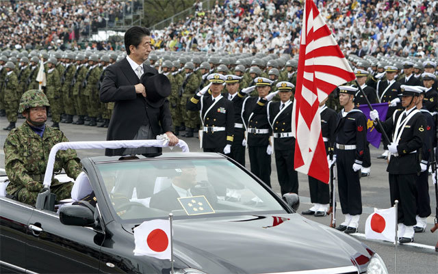 14일 오전 일본 사이타마현 육상자위대 아사카훈련장에서 열린 자위대 사열식에서 아베 신조 총리가 탑승한 오픈카가 욱일기 앞을 지나고 있다. 이날 아베 총리는 자위대의 존재를 헌법에 명시하겠다고 밝혔다. 사이타마=AP 뉴시스