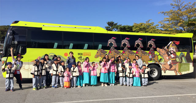 백제 계백 장군 등의 이미지를 입힌 ‘백시달 EQ 버스’ 앞에서 백제 복식으로 차려입은 관광객들이 손을 흔들고 있다. 부여군 제공