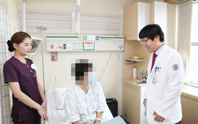인하대병원 이진욱 교수(오른쪽)가 갑상선암으로 ‘구강 경유 내시경 수술’을 받은 박모 씨(가운데)를 진료하고 있다. 인하대병원 제공
