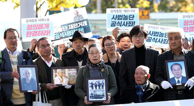 이춘식 씨(앞줄 오른쪽에서 두 번째) 등 일제 강제징용 손해배상 청구 소송 관계자들이 30일 오후 상고심 선고에 앞서 서울 서초구
 대법원 대법정으로 향하고 있다. 사진을 들고 있는 왼쪽 끝의 두 남성은 일본과 한국을 오가며 21년간 이번 소송을 도운 일본인 
우에다 게이시 씨(왼쪽)와 나카타 미쓰노부 씨. 뉴시스