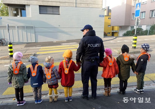 스위스 취리히 리마트구트 유치원 어린이들이 교통안전교육을 받은 뒤 실습을 하고 있다. 왕복 2차로인데도 보행 약자를 위해 교통섬이 설치돼 있다.