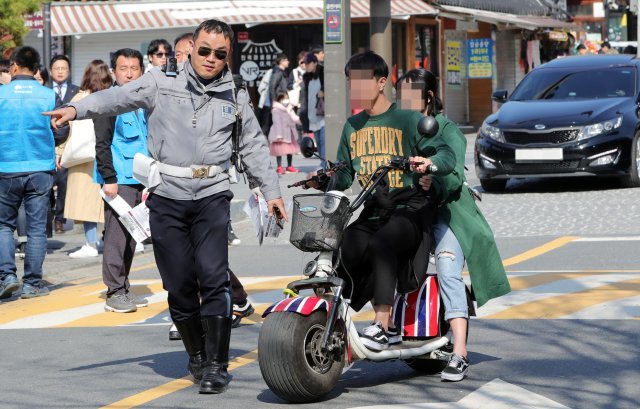 23일 오후 전북 전주시 한옥마을 태조로에서 교통경찰과 전주시 한옥마을지원과 직원들이 안전모를 안쓰고 전동이동장치를 탄 관광객에게 계도 및 홍보활동을 하고 있다. /뉴스1 DB © News1