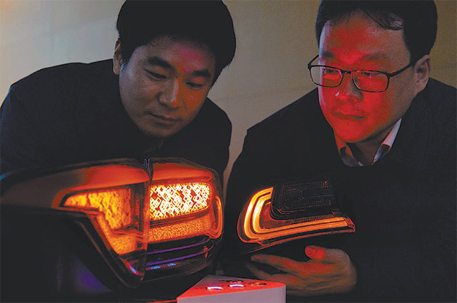 19일 경기 용인시 현대모비스 기술연구소에서 램프선행설계팀 김정영 책임연구원(왼쪽)과 민경구 연구원이 램프를 살피고 있다. 왼쪽 램프가 모비스가 만든 3차원(3D) 램프고, 오른쪽이 기존의 일반 램프다. 현대모비스 제공