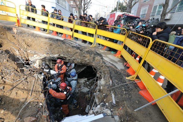 경찰과 소방대원들이 25일 오전 서울 서대문구 충정로 KT아현국사 앞 공동구 화재현장에서 전날 발생한 화재 원인을 조사하기 굴착기로 땅을 파고 현장 감식을 하고 있다.2018.11.25/뉴스1 © News1