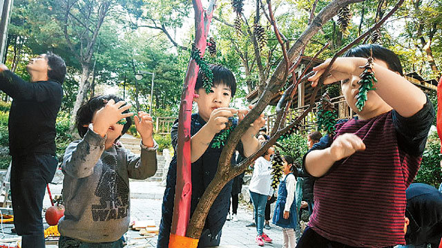 10월 ‘책엄책아’의 ‘마을 숲 정원에서 예술하기’ 프로그램에 참여한 아이들이 솔방울로 나무를 장식하는 모습. 책엄책아 제공