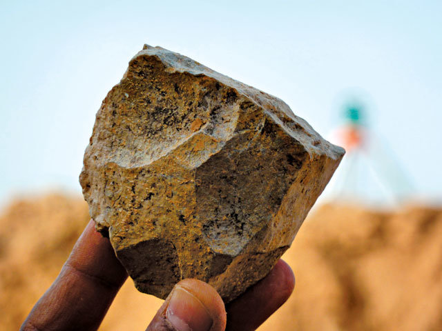 올도완 석기를 연구자가 들어 보이고 있다. 돌을 내리쳐 날카로운 조각(격지)을 떼어냈다. 사진 출처 사이언스